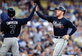  ?? MARK J. TERRILL / The Associated Press ?? Atlanta’s Freddie Freeman (right) gets a high five from teammate Dansby Swanson during Saturday’s game against the Los Angeles Dodgers after they both scored on a Tyler Flowers’ double in the third inning.