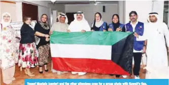  ??  ?? Yousef Mustafa (center) and the other attendees pose for a group photo with Kuwait’s flag.
