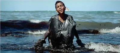  ??  ?? Spiagge contaminat­e Un ragazzo cerca di pulire dal petrolio il litorale a Cabo de Santo Agostinho, in Brasile