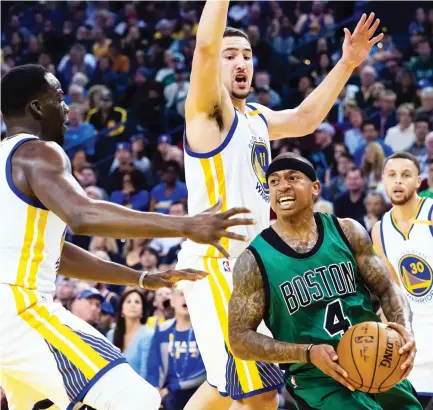  ??  ?? Boston Celtics guard Isaiah Thomas (4) controls the ball between Golden State Warriors forward Draymond Green (23), guard Klay Thompson (11) and guard Stephen Curry (30) during the third quarter at Oracle Arena on Wednesday night. (USA TODAY Sports)