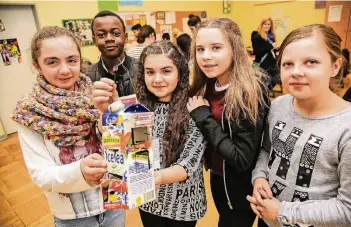  ?? FOTO: LARS FRÖHLICH ?? Sezen, Amos, Sude und Alija (von links) zeigen, wie aus einer leeren Getränketü­te eine Laterne für den Martinszug am Freitag werden kann.