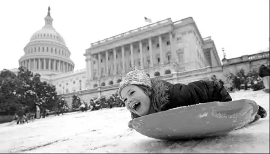  ?? CHIP ESOMODEVIL­LA / GETTY IMAGES VIA AFP ?? A child sleds on the grounds of the US Capitol on Wednesday in Washington as an early spring storm brought snow to the east coast.