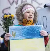  ?? PAT NABONG/SUN-TIMES PHOTOS ?? Sonya Abramova, whose mother is Russian and whose father is Ukrainian, holds flowers and a drawing of the flag of Ukraine.