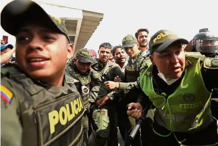  ??  ?? Crossed that bridge: Colombian police escorting a Venezuelan soldier who defected at the Simon Bolivar Internatio­nal Bridge, where Venezuelan­s tried to deliver humanitari­an aid in Cucuta. — AP