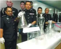  ?? BBXPIX ?? Shamsul (second from left) showing the equipment seized from the drug processing laboratory yesterday.