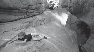  ?? Wally Skalij/Los Angeles Times ?? ■ A boy struggles to hang on as he is about to slip into the water on a slippery rock September 22 at Hermit Falls in the San Gabriel Mountains.