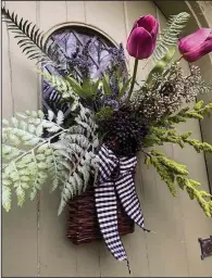  ??  ?? This willow basket filled with black and white check ribbon, amaranths stem, Boston fern, royal fern, lavender Pick, burgundy seed bunch, purple long seed stem and large plum tulips.