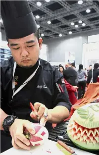  ??  ?? Mohamad Fadzly Che Omar pays full attention as he is demonstrat­ing his fruit carving skills at the UCSI booth.