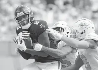  ?? HANS DERYK/AP ?? Falcons tight end Kyle Pitts makes a catch, defended by Dolphins cornerback Xavien Howard, center, and free safety Jevon Holland during the second half Sunday in Miami Gardens.