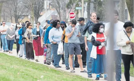  ?? Lauren Justice, © The New York Times Co. ?? People wait in line to vote at Milwaukee’s Marshall High School on Tuesday. Wisconsin became the first state to hold a major election with in-person voting since stay-at-home orders were widely instituted because of the coronaviru­s pandemic.