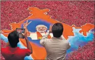  ?? [SAURABH DAS/THE ASSOCIATED PRESS] ?? In this May 16, 2014, file photo, Indians take photograph­s of a portrait of Bharatiya Janata Party leader Narendra Modi, with an outline of the India map made with colored powder and surrounded by rose petals, in Gandhinaga­r, Gujarat state, India. Modi, who became a Hindu nationalis­t before he was 10 years old, has upended life in India's only Muslim-majority state, flexing those nationalis­t muscles for his millions of followers.