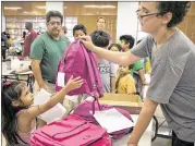  ?? PHOTOS BY RALPH BARRERA/ AMERICAN-STATESMAN ?? Jimena Hurtah Mireles, 5, gets her newbackpac­k Monday morning with the help of volunteerA­sa McDaniel, 13. For the past 17 years, Manos de Cristo has been giving away school supplies.