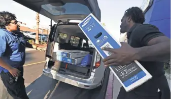  ?? MARK RALSTON, AFP/GETTY IMAGES ?? Best Buy workers load a TV during a Black Friday sale in Los Angeles. Many stores’ deals were still available Sunday.