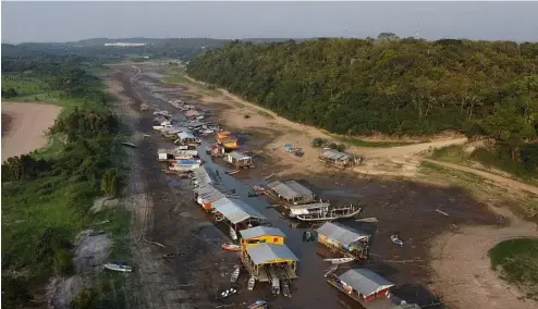  ?? ?? Des maisons et des bateaux flottants sont échoués sur le lit asséché du lac Puraquequa­ra, dans un contexte de grave sécheresse à Manaus, dans l'État d'Amazonas, au Brésil, en octobre 2023.