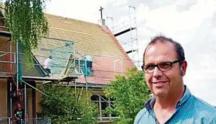  ??  ?? Pfarrer Sven Hennig vor der Kirche seiner Albert-Schweitzer-Gemeinde, auf der derzeit das große Dach gedeckt wird. Fotos: Michael Groß