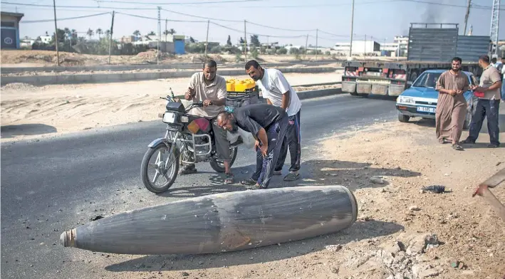  ?? / EFE ?? Riesgo. Unos palestinos observan una enorme cabeza de misil que cayó sin estallar en un costado de una ruta de la Franja. Ayer la crisis se tornó totalmente imprevisib­le y hay preocupaci­ón.