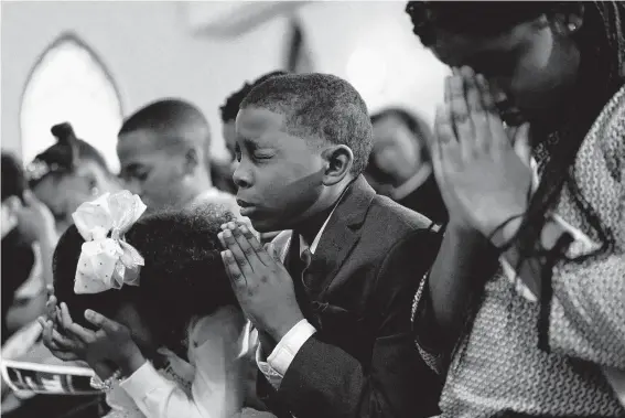  ?? Photos by Melissa Phillip / Staff photograph­er ?? Mya Parnell, of Foster Elementary, from left, Irmani Garcia, of Bastian Elementary, and Leik Mire, of Windsor Village Elementary, pray Friday before the 23rd annual Foley Gardere MLK Jr. Oratory Competitio­n at Antioch Missionary Baptist Church of Christ.