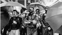  ?? ANTHONY KWAN/GETTY ?? Masked demonstrat­ors mobilize on Sunday during a massive rally to mark six months of pro-democracy protests in Hong Kong. Thousands of people marched in the streets.