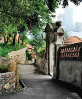  ??  ?? The modern buildings across the Lujiang River in downtown Xiamen are visible through the porch of an old building on Gulangyu Island. VCG