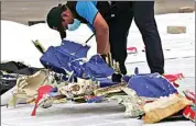  ?? TATAN SYUFLANA / AP ?? An investigat­or of Indonesian National Transporta­tion Safety Committee inspects parts of Sriwijaya Air Flight 182 that crashed in the waters off Java Island, at Tanjung Priok Port in Jakarta, Indonesia, on Sunday.