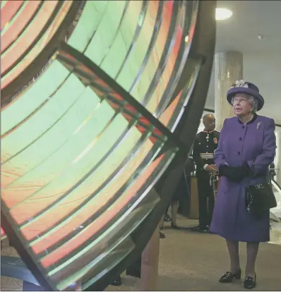  ??  ?? LIGHT TOUCH: The Queen looks at an optic from a decommissi­oned Suffolk lighthouse at the Internatio­nal Maritime Organizati­on, London.