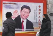  ?? Greg Baker / AFP / Getty Images ?? Pedestrian­s in Beijing pass a poster of President Xi Jinping, who is seeking to eliminate term limits.