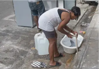  ??  ?? Una señora se abastece de agua en el barrio 27 de Febrero en la capital.