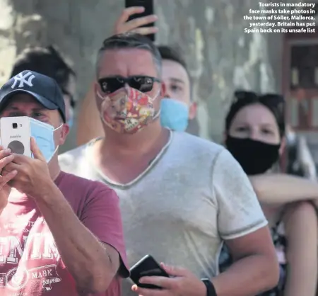  ??  ?? > Tourists in mandatory face masks take photos in the town of Sóller, Mallorca, yesterday. Britain has put Spain back on its unsafe list