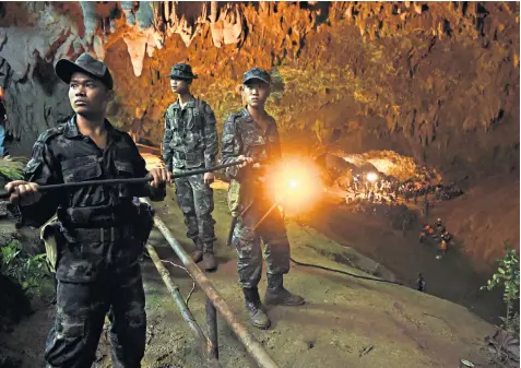  ??  ?? Thai soldiers relay electric cable deep into the three-mile long cave in Khun Nam Nang Non Forest Park to provide light for the divers, who face flood water up to 21ft deep