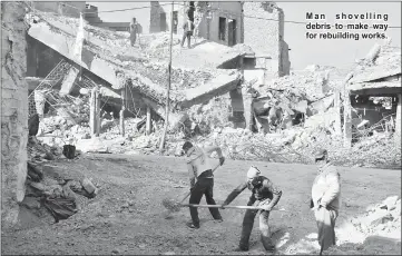  ??  ?? Man shovelling debris to make way for rebuilding works.