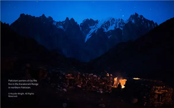  ?? © Krystle Wright. All Rights Reserved. ?? Pakistani porters sit by the fire in the Karakoram Range in northern Pakistan.