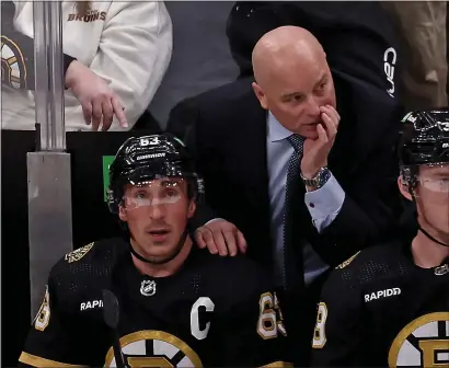  ?? STUART CAHILL — BOSTON HERALD ?? Boston Bruins head coach Jim Montgomery and left wing Brad Marchand look on from the bench as the Bruins take on the Senators at the TD Garden on Tuesday.