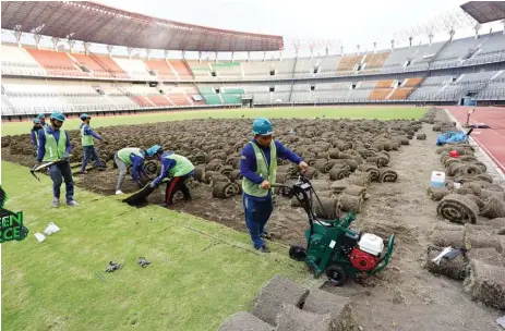  ?? ANGGER BONDAN/JAWA POS ?? BELUM BISA DIGUNAKAN: Petugas tengah membongkar rumput lapangan di Stadion Gelora Bung Tomo Rabu lalu (5/8). Rumput akan diganti yang sesuai standar FIFA.