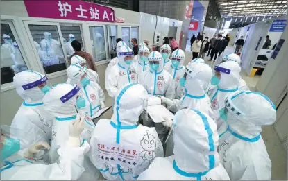  ?? PHOTOS BY ZHU XINGXIN / CHINA DAILY ?? Medical workers from Hubei check informatio­n at a makeshift hospital in Pudong New Area, Shanghai.