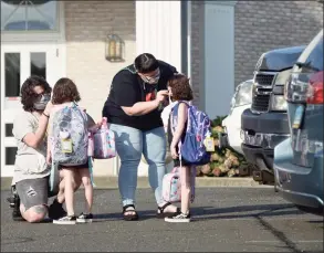  ?? H John Voorhees III / Hearst Connecticu­t Media file photo ?? Ian Copland, left, and Megan Tucker, of Danbury, adjust their twin daughters Lilith, left, and Lydia Copland masks while dropping them off for the first day of kindergart­en in August at the Danbury Primary Center in Brookfield. Some are calling for schools to be permitted to temporaril­y go to remote learning due to the COVID-19 surge and staff shortages.