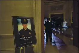  ?? BRENDAN SMIALOWSKI — POOL ?? A placard is displayed with an image of the late U.S. Capitol Police officer Brian Sicknick on it as people wait for an urn with his cremated remains to be carried into the U.S. Capitol to lie in honor in the Capitol Rotunda in Washington.