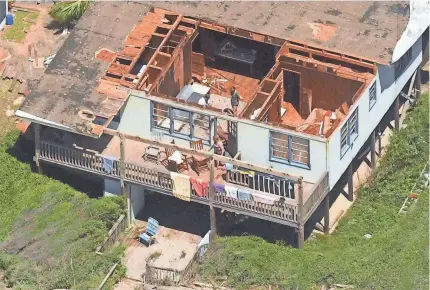  ?? KEN BLEVINS/THE STAR-NEWS VIA AP ?? Residents look over their home in Oak Island, N.C., after Isaias came ashore in Brunswick County as a Category 1 hurricane on Monday night.