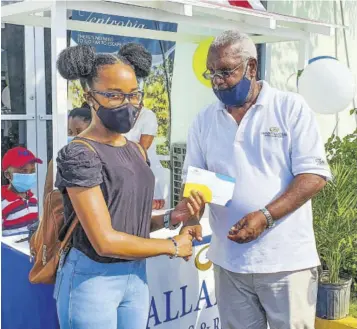  ?? (Photo: Anthony Lewis) ?? Jey-ann Hayles (left) collects a cheque from Leroy Peart, president of the resort’s staff associatio­n, during the recent Grand Palladium Resorts and Spa’s back-toschool fair.