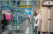  ?? LORI WASELCHUK/FOR THE WASHINGTON POST ?? Amanda Haviland, a QVC client sample coordinato­r, steam irons clothes inside the shopping giant’s “Product Central” warehouse.