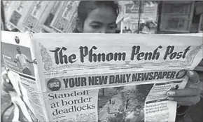  ??  ?? A woman reads a newspaper by the Phnom Penh Post, who has been sold to the owner of a Malaysian PR company. (Photo: Getty Images)