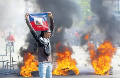  ?? AP ?? A demonstrat­or holds up an Haitian flag during protests demanding the resignatio­n of Prime Minister Ariel Henry in Port-au-Prince.