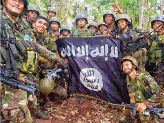  ??  ?? Military photo shows army soldiers posing with an ISIS flag in Basilan province in southern Philippine­s where security forces are battling the Abu Sayyaf.