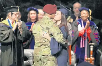  ?? AMY BETH BENNETT/STAFF PHOTOGRAPH­ER ?? Pvt. J.P. Gomes kisses his wife, Selena Gomes, after surprising her at her graduation Friday at Florida Atlantic University in Boca Raton.