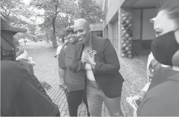  ?? STEVEN SENNE/AP ?? U.S. Rep. Ayanna Pressley, D-mass., center, greets people in July by clasping her hands over her chest in Boston’s Roxbury neighborho­od. The question of how or if to shake hands is a thorny one in the age of coronaviru­s and vaccines.