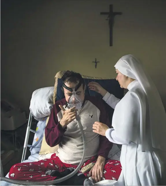  ??  ?? SISTER MARIA de Jesús Campos tends to Refugio Vega, who has been living with ALS for more than six years, with Vega’s wife, Sara Montiel de Vega, at his side. The Servants of Mary pray with all clients regardless of their faith.
