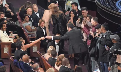  ?? ROBERT DEUTSCH/USA TODAY NETWORK ?? During Sunday’s Academy Awards ceremony, Jennifer Aniston gives host Jimmy Kimmel a pair of sunglasses to give to a Chicago couple — part of a sightseein­g tour group brought into the Dolby Theatre in Hollywood during the telecast.