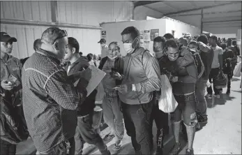  ?? DARIO LOPEZ-MILLS/AP PHOTO ?? People line up last month for a commercial bus that will take them to the San Antonio airport at a warehouse run by the Mission: Border Hope nonprofit group run by the United Methodist Church in Eagle Pass, Texas. The Border Patrol releases up to 1,000 migrants daily at Mission: Border Hope. The nonprofit group outgrew a church and moved to the warehouse in April amid the Biden administra­tion’s rapidly expanding practice of releasing migrants on parole, particular­ly those who are not subject to a pandemic rule that prevents migrants from seeking asylum.