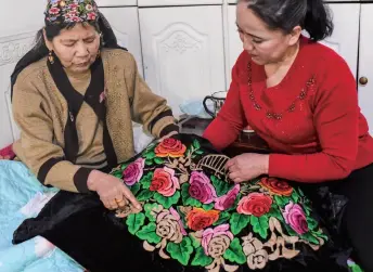  ??  ?? Two craftswome­n in Hami City, northwest China’s Xinjiang Uygur Autonomous Region, discuss embroidery skills on March 6