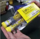  ?? RICH PEDRONCELL­I — THE ASSOCIATED PRESS FILE ?? In this file photo, a pharmacist holds a package of EpiPens epinephrin­e auto-injector, a Mylan product, in Sacramento Mylan said it will make available a generic version of its EpiPen, as criticism mounts over the price of its injectable medicine.