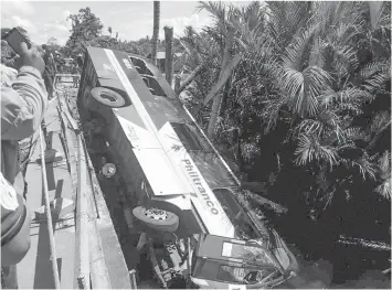  ??  ?? The ill-fated Philtranco passenger bus, bound for Surigao del Norte from Pasay City, lies on its side after it went off the bridge into the swamp below along the highway in Tanauan, Leyte. Three passengers are confirmed dead and 49 others are injured...